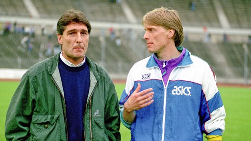 Rudi Assauer und Wolfgang Sidka laufen zu Beginn der 1990er-Jahre gemeinsam über den Platz.