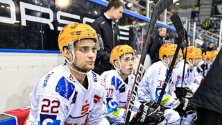 Pinguins-Spieler sitzen auf der Bank und schauen nachdenklich.