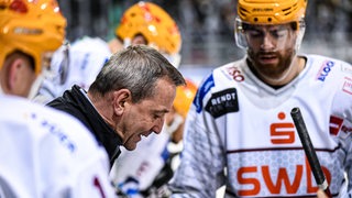 Pinguins-Coach Thomas Popiesch erklärt seinen Spielern an der Bande die Taktik.