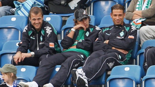 Die Werder-Profis Daniel Jensen, Pascal Testroet und Tim Wiese sitzen auf der Tribüne und beobachten ein Spiel.
