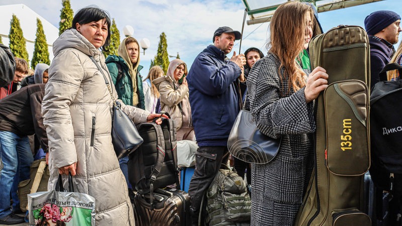 Ukraine-Geflüchtete warten mit ihrem Gepäck auf einem Busbahnhof.