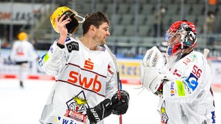 Tye McGinn hält seinen Helm im Arm und unterhält sich mit Maximilian Franzreb.
