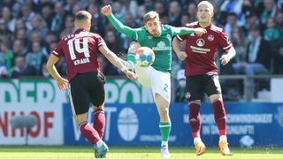 Werders Romano Schmid behauptet den Ball gegen zwei Nürnberger Gegenspieler.