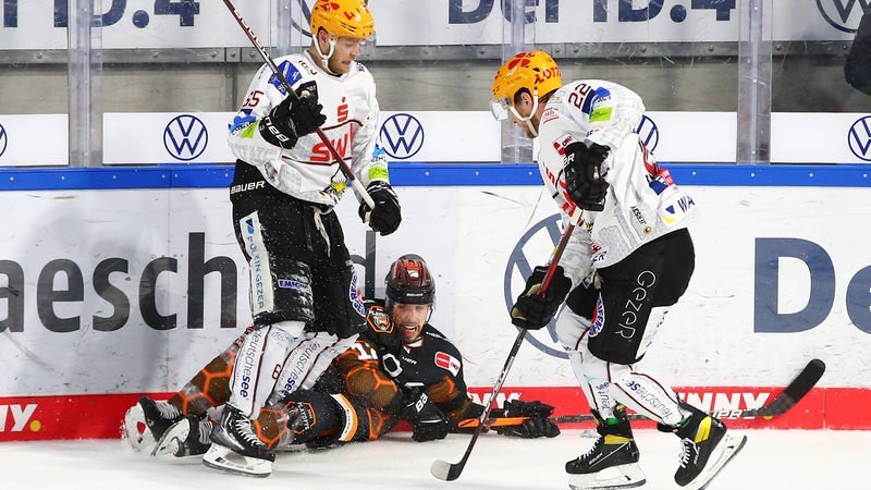 Zwei Pinguins-Spieler versuchen, einem Wolfsburg-Spieler den Puck abzunehmen.