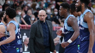 Eisbären-Coach Allen Ray Smith steht mit nachdenklicher Miene zwischen seinen Spielern.