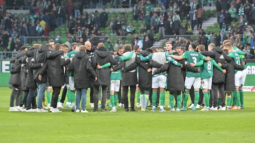 Die Werder-Mannschaft mit Trainer- und Betreuerstab steht Arm in Arm im Kreis nach dem Spiel.