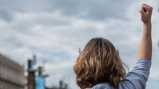 Eine Frau streckt auf einer Demonstration die Faust in die Luft.