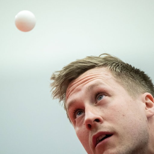 Tischtennis-Profi Mattias Falck in Nahaufnahme, wie er beim Aufschlag den Ball in der Luft anvisiert.