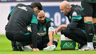 Werder-Kapitän Ömer Toprak liegt verletzt auf dem Platz.