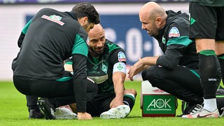 Werder-Kapitän Ömer Toprak liegt verletzt auf dem Platz.