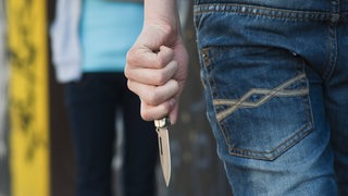 Ein Junge hält ein Messer in der Hand und bedroht ein weiteres Kind. 