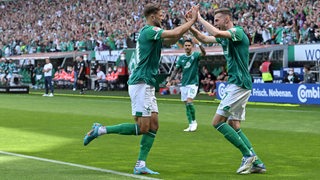 Die Werder-Stürmer Marvin Ducksch und Niclas Füllkrug klatschen sich jubelnd nach Füllkrugs Treffer gegen Regensburg ab.
