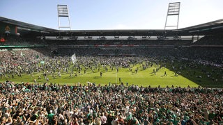 Nach dem Abpfiff gegen Regensburg stürmen die Werder-Fans den Rasen. 