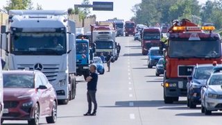 Mehrere Menschen haben nach einem Stau auf einer Autobahn ihre Wagen verlassen.