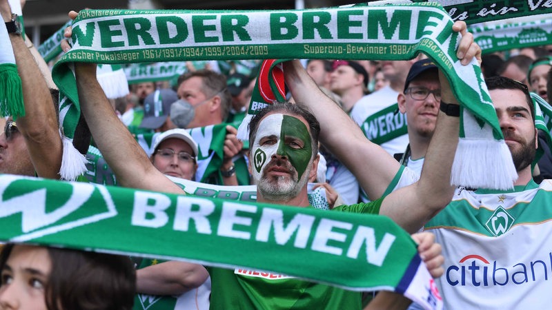 Werder-Fans halten ihre Schals im Stadion hoch.