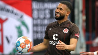 Kyereh lächelt mit einem Ball in der hand.