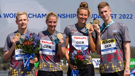 Florian Wellbrock posiert gemeinsam mit der Deutschen Staffel mit der Medaille.