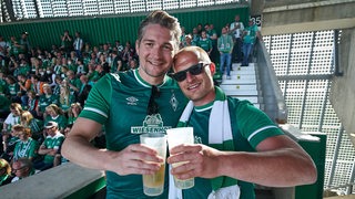 Zwei Werder-Fans stoßen mit Bier an.