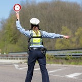 Eine Polizistin winkt mit einer Kelle Autofahrer heraus.