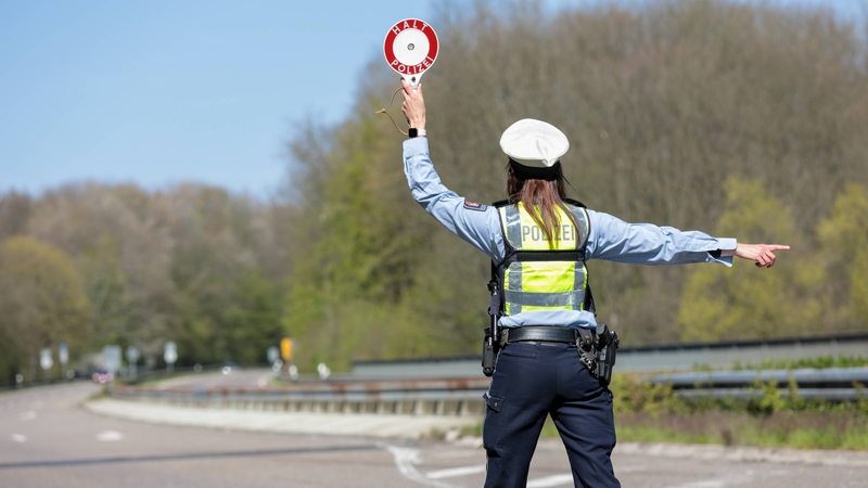 Eine Polizistin winkt mit einer Kelle Autofahrer heraus.