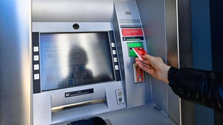 Eine Frau führt ihre Bankkarte zu einem Geldautomaten.