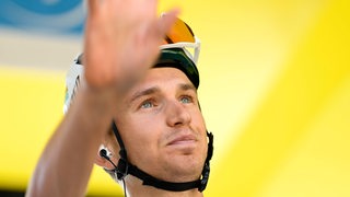 Radprofi Lennard Kämna winkt den Fans vor einem Etappenstart bei der Tour de France.