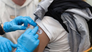 Bei einem Impftermin für Kinder wird einem Kind nach der Impfung ein Pflaster auf die Einstichstelle geklebt. 