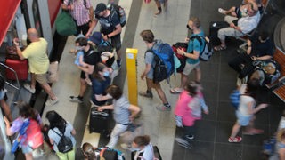 Viele menschen drängen sind an einem Bahngleis.