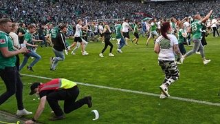 Fans stürmen im Weser-Stadion auf dem Platz.