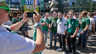 Fan vor dem Weser-Stadion mit Ole-Werner-Masken werden fotografiert.