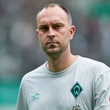 Werder_Trainer Ole Werner schreitet mit nachdenklichem Gesichtsausdruck über den Platz.