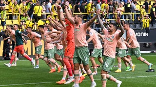 Die Werder-Spieler fassen sich an den Händen und feiern ausgelassen vor dem Werder-Fanblock den Sieg gegen Dortmund.