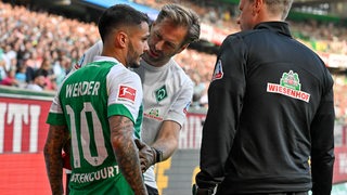 Leonardo Bittencourt wird an der Seitenlinie von Werders Mannschaftsarzt wegen einer Zerrung der Rippen behandelt.