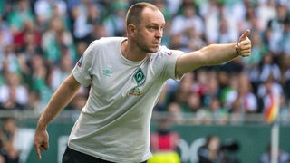 Werder-Trainer Ole Werner beugt sich nach vorne und gibt Anweisungen.