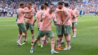 Werder-Spieler kommen nach einem Tor in einer Jubeltraube zusammen, Marco Friedl schreit mit martialischer Geste.
