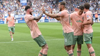 Werder-Spieler jubeln nach einem Tor, Oliver Burke und Niclas Füllkrug klatschen sich ab.