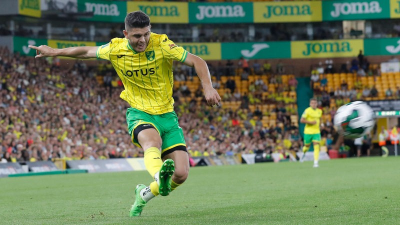 Milot Rashica im gelben Trikot für Norwich City bei einem dynamischen Schuss.