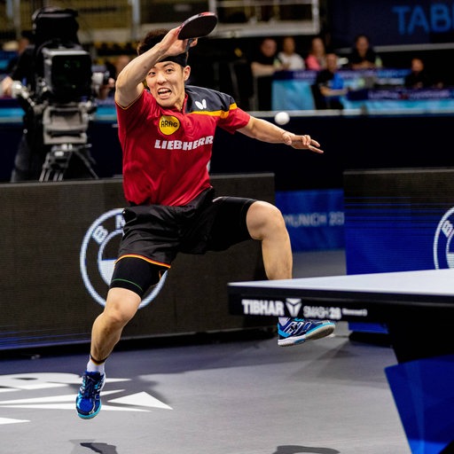 Tischtennis-Profi Dang Qiu bei einem energiegeladenen Vorhandschlag im Sprung.
