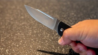 Eine Person hält ein Messer in der Hand.