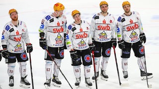 Eishockey-Spieler der Fischtown Pinguins stehen nach einem Spiel ausgepowert aufgereiht nebeneinander auf dem Eis.