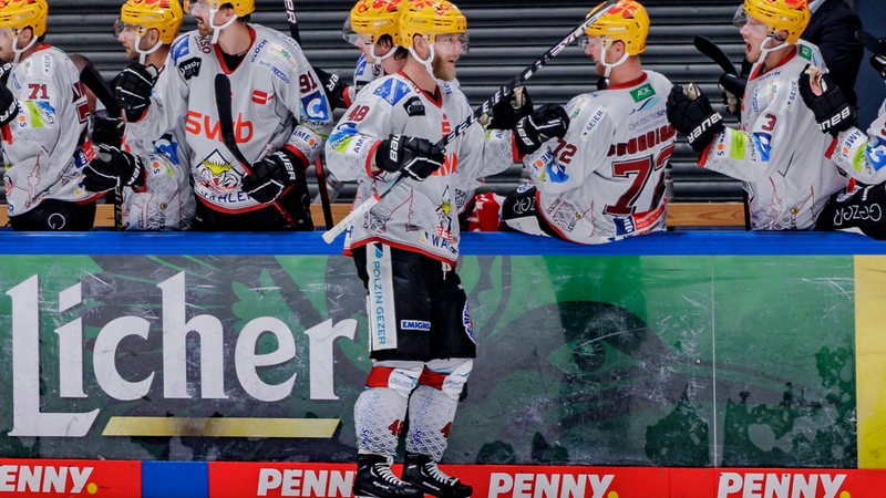 Eishockey-Spieler der Fischtown Pinguins stehen an der Bande und klatschen Nicholas Jensen ab.