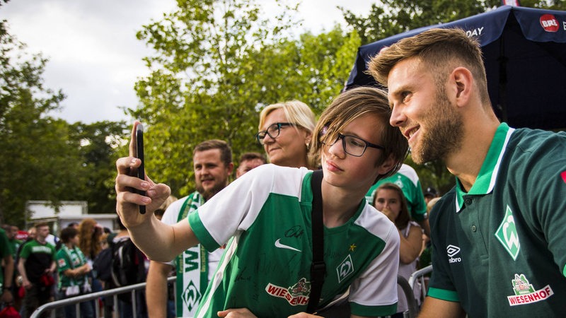 Ein junger Fan macht ein Foto mit Füllkrug.