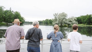 Großeltern und Enkel stehen gemeinsam am Wasser.