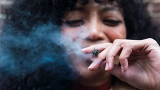 Eine Frau raucht einen Cannabis-Joint.