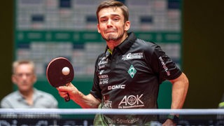 Werders Tischtennis-Spieler Kirill Gerassimenko mit schmerzverzerrtem Gesicht bei einem Vorhandschlag.