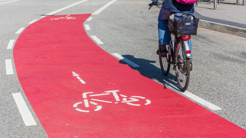 Ein Radfahrer fährt auf einer rot markierten Fahrradstraße.