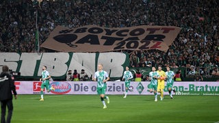 Während die Werder-Spieler ins Weser-Stadion einlaufen, halten die Fans ein "Boycott Katar"-Banner hoch.