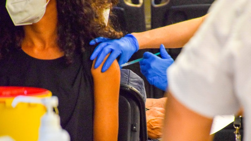 Eine Frau bekommt eine Corona-Impfung in den Oberarm.