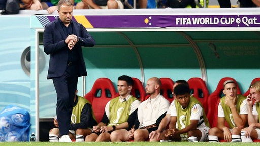 Bundestrainer Hansi Flick steht vor der Ersatzbank und schaut während des Spiels gegen Spanien auf seine Uhr.