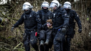 Vier Polizisten tragen einen Demonstranten weg